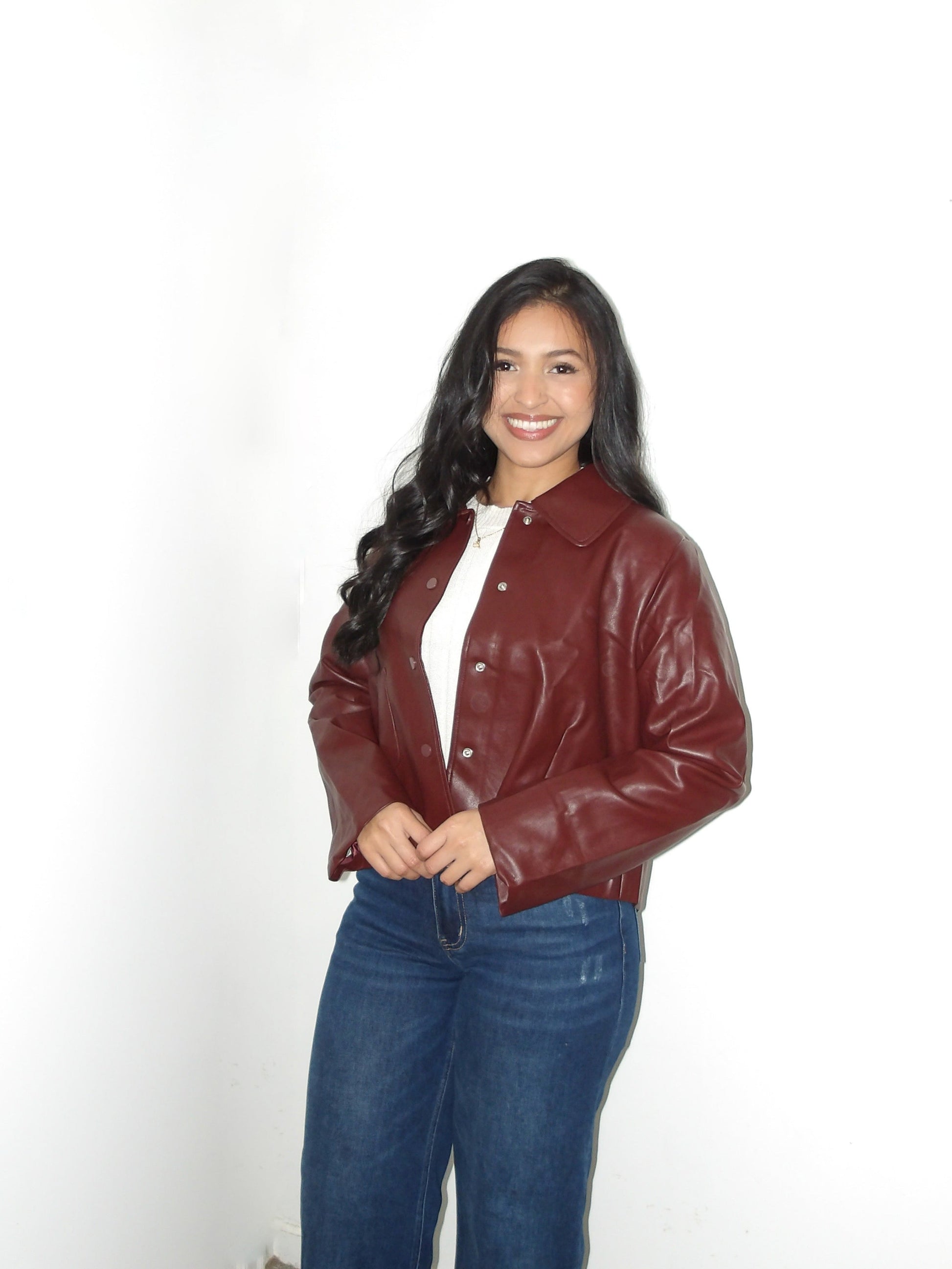 Woman wearing a brown leather jacket and blue jeans against a white background