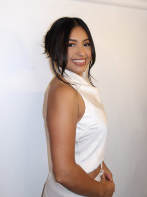 Woman wearing a white top with a plain background