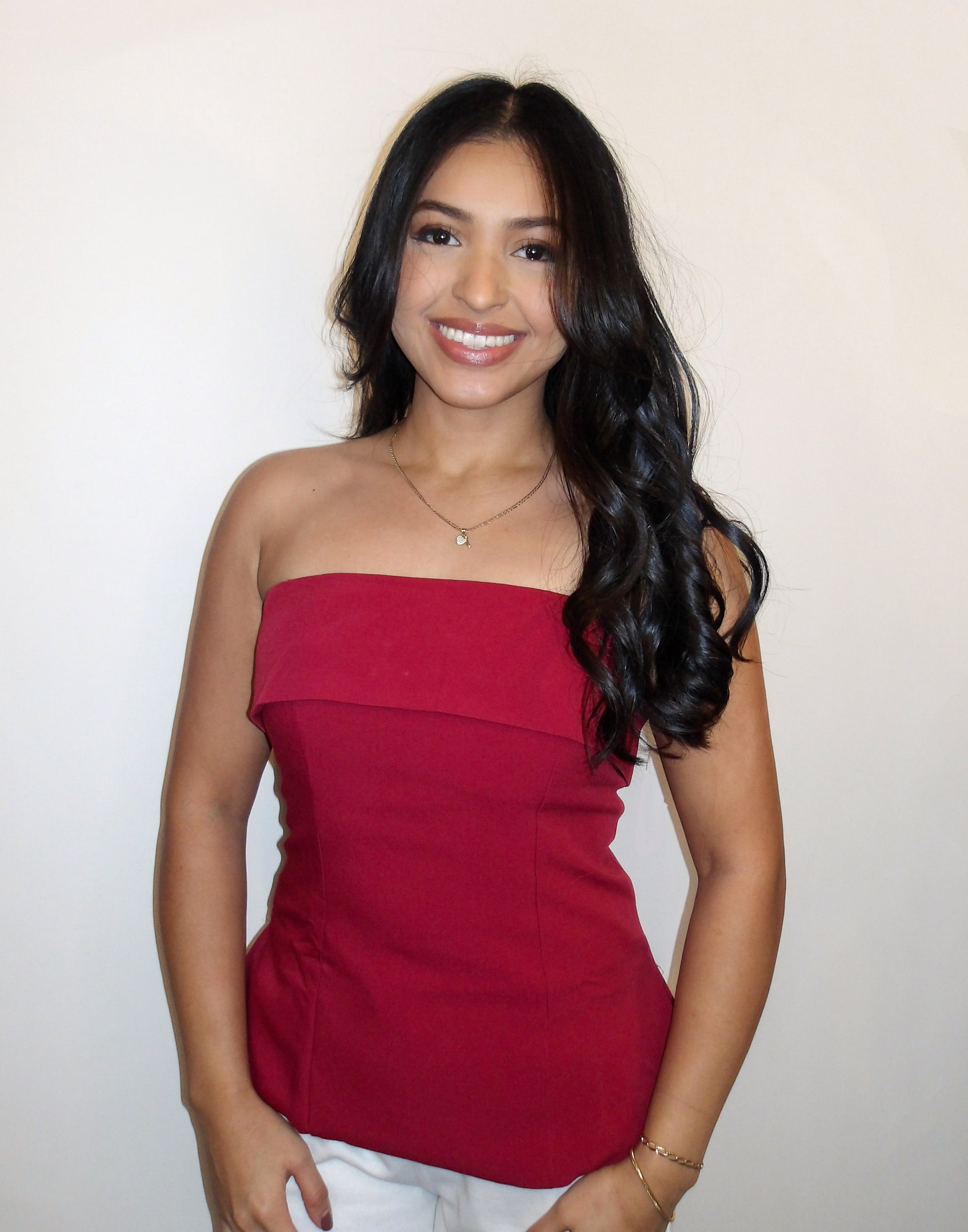 Woman wearing a red strapless top against a plain background